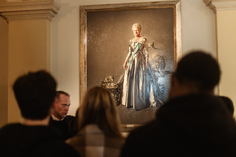 Steffen lecturing in front of Queen Margrethe II's portrait inside Christiansborg Palace.