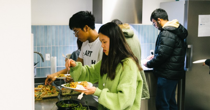 Students serve themselves food in a communal kitchen.